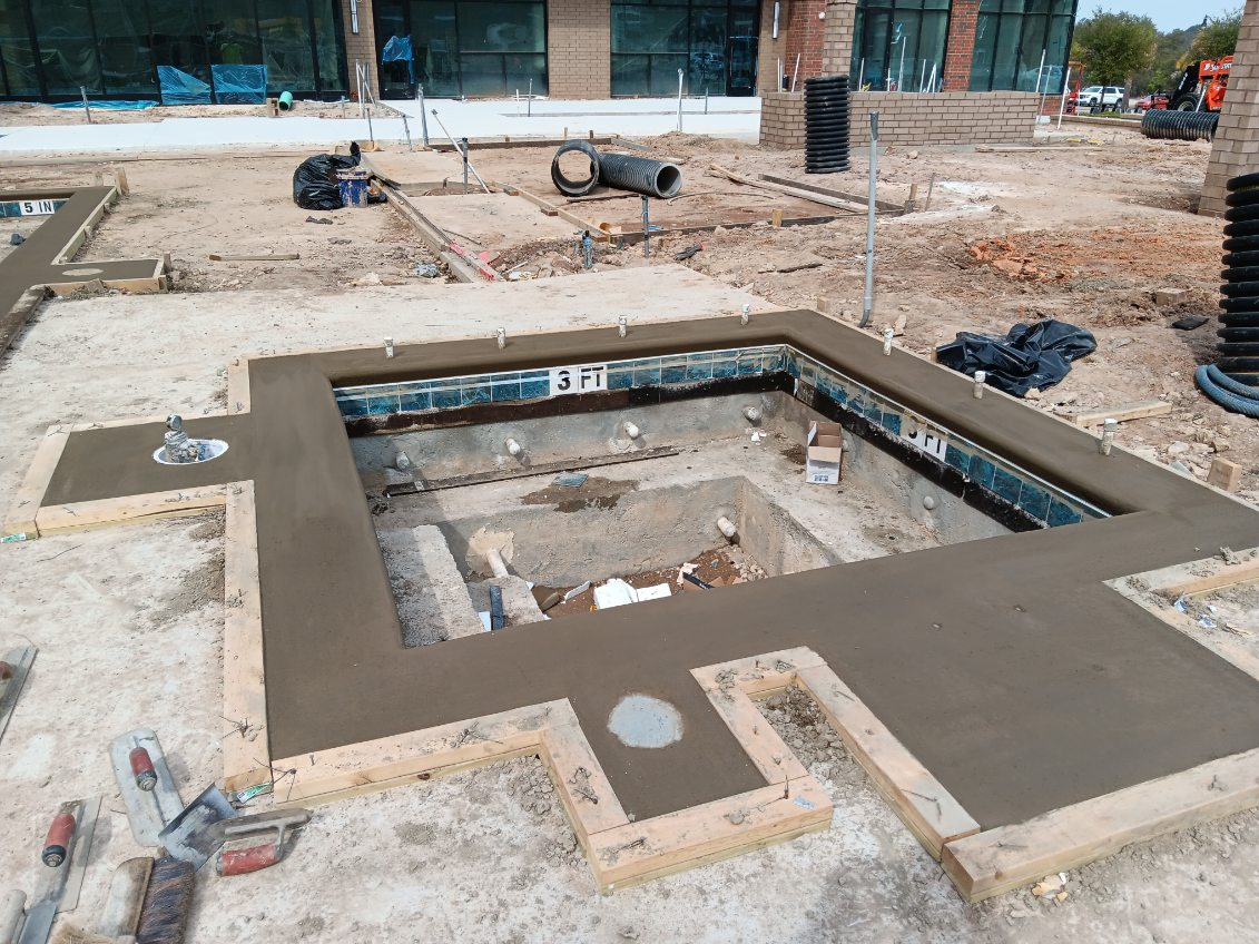 Construction progress — coping complete, pool and spa shells taking shape ahead of finish work.