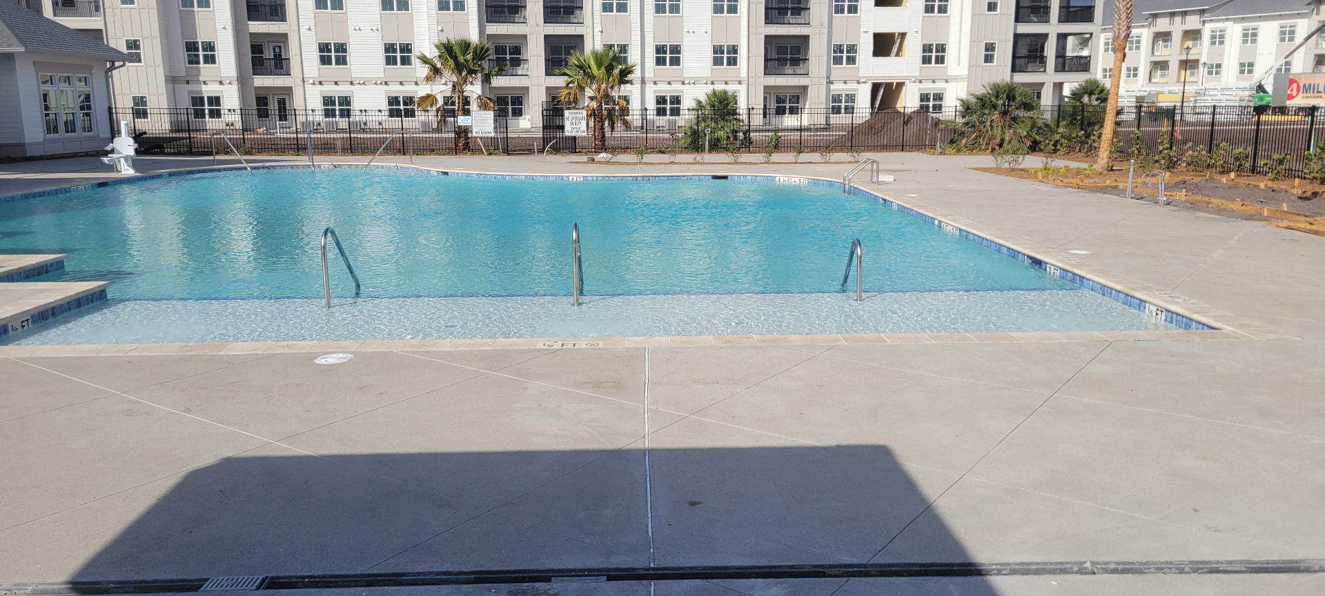 Finished pool with depth markers, handrails, and surrounding deck.